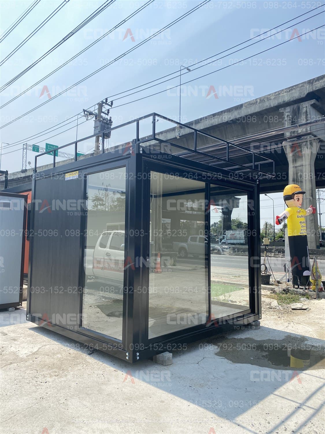 ตู้ร้านค้า รุ่น PH 2 x 3 เมตร ตั้งริมถนน เห็นกระจกรอบด้านและโครงอะลูมิเนียมสีดำ พร้อมราวกันตกบนหลังคา