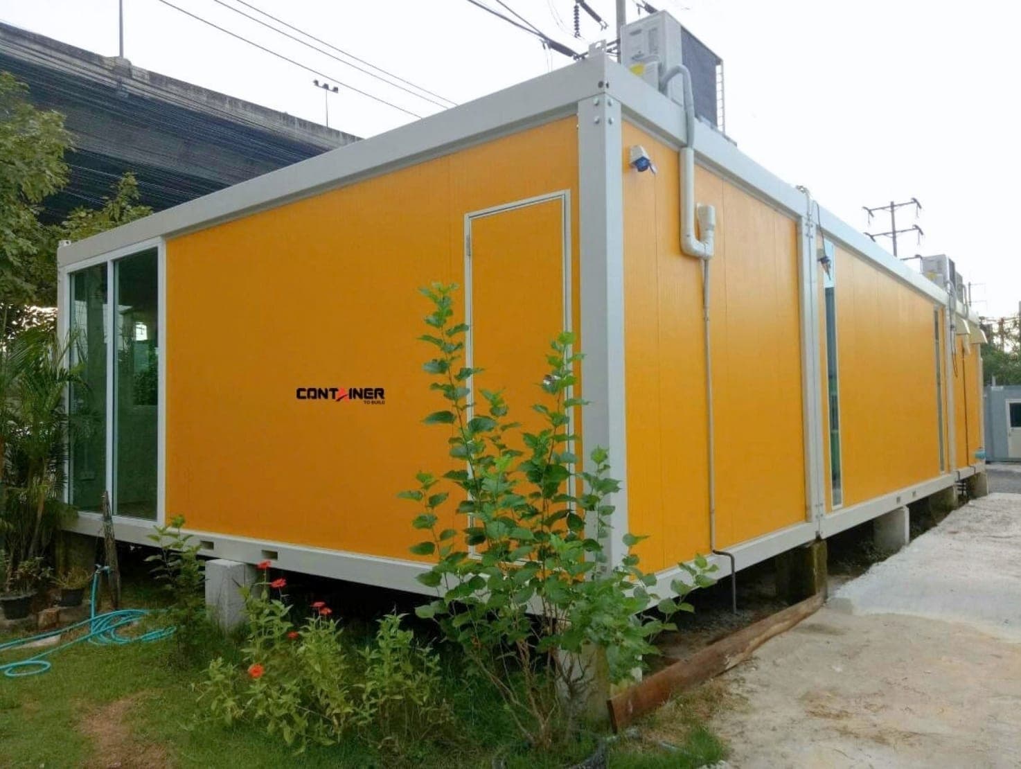 บ้านน็อคดาวน์ รุ่น WL มองจากด้านข้าง เห็นความยาวตัวบ้านและคอมเพรสเซอร์แอร์บนหลังคา
