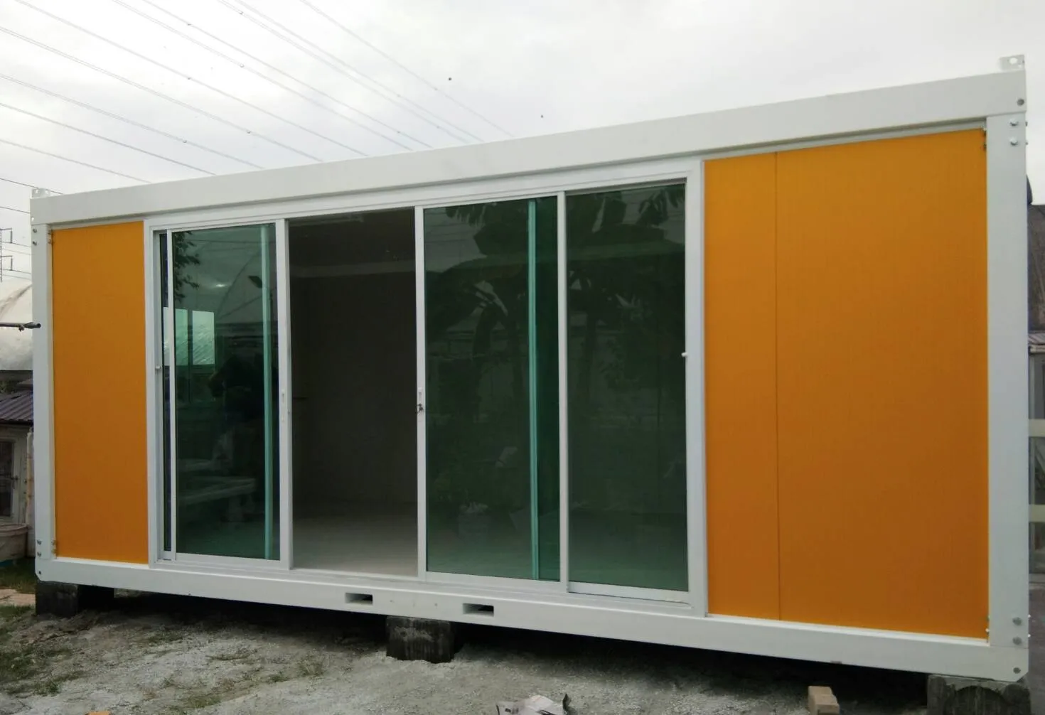 Knock-down office unit with orange walls and white frame, a person standing beside it for scale