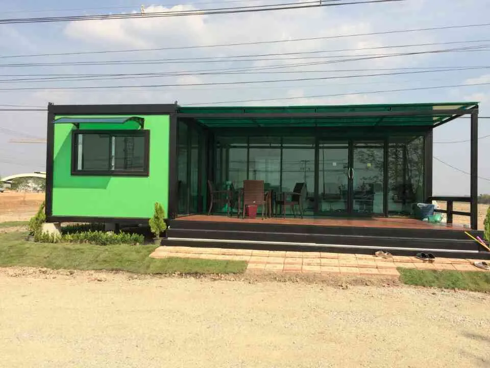 Knock-down café with bright green walls, full glass front, polycarbonate roof and a wooden deck with tables (view 2)