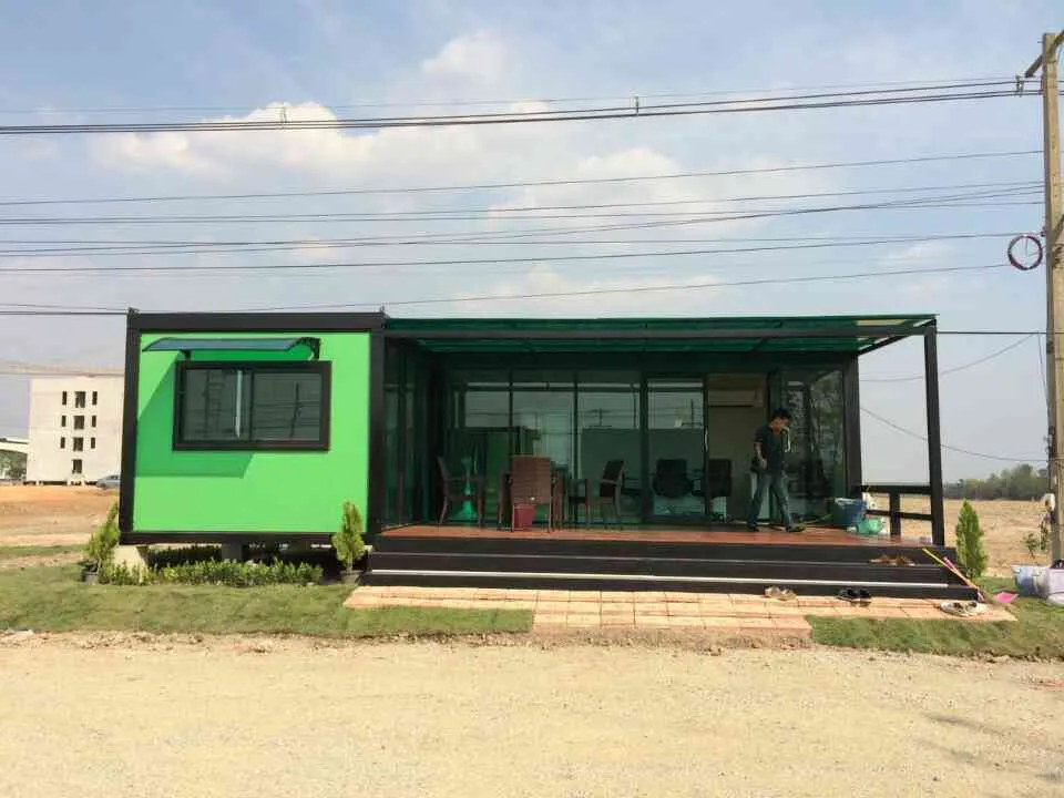 Knock-down café with bright green walls, full glass front, polycarbonate roof and a wooden deck with tables (view 3)
