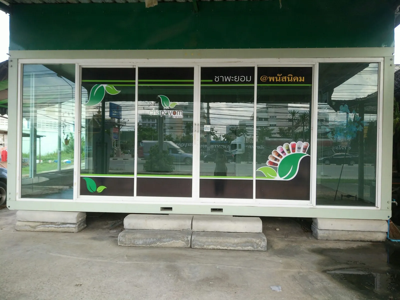 Knock-down shop unit with full-width sliding glass, brand graphics on the glass, set on concrete blocks