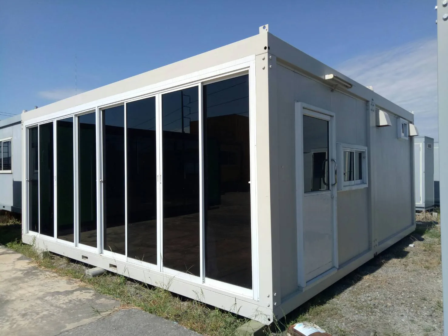 White knock-down office unit with an almost fully glazed front and a side door and window